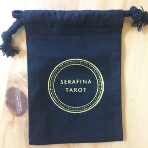 May include: Black drawstring bag with a gold circle logo that says "SERAFINA TAROT".
