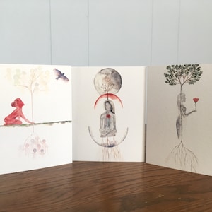May include: Three watercolor art cards featuring ethereal figures and nature elements. One card depicts a red figure with a tree and bird, another shows a seated figure with a moon, and the last shows a figure holding a rose with a tree.