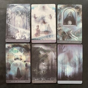 Op de afbeelding: Zes tarotkaarten uit het Shadow deck, met een donkere, sfeervolle esthetiek. De kaarten zijn: Vijf van Schaduw, Vier van Schaduw, Student van Schaduw, Aas van Schaduw, Beheerder van Schaduw en Soeverein van Schaduw.