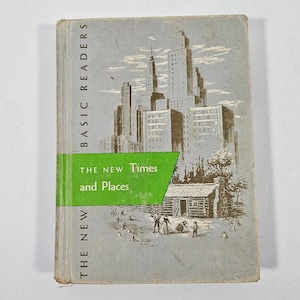 May include: A vintage hardcover book titled Basic Readers: The New Times and Places. The gray cover features a brown ink illustration of a city skyline above a log cabin and figures. A bright green horizontal band overlays the center of the cover.