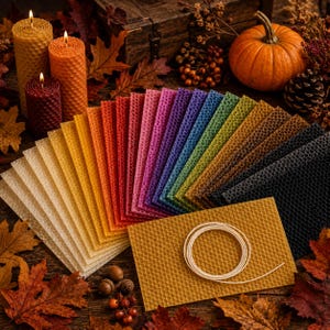 Può includere: Una collezione di fogli rettangolari di cera d'api in uno spettro di colori che include bianco, giallo, arancione, rosso, rosa, viola, blu, verde, marrone e nero, disposti a ventaglio, con uno stoppino di cotone bianco su un foglio giallo.