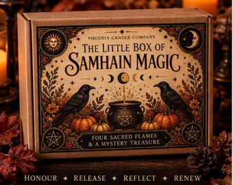 May include: A rectangular cardboard box labeled The Little Box of Samhain Magic by Phoenix Candle Company. The front features illustrations of two black crows, pumpkins, a cauldron with a pentagram, a sun, a moon, and text.