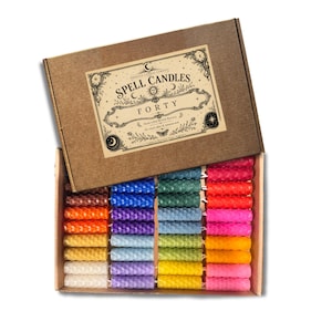May include: A box of forty spell candles in various colors, including orange, yellow, green, blue, and pink. The box is brown with a decorative label that reads "Spell Candles Forty". The candles are arranged neatly inside the open box.