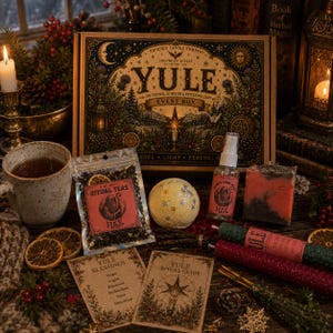 May include: A Yule event box set featuring a large illustrated box, a bag of ritual tea, a round bath bomb with gold stars, a spray bottle, a rectangular soap bar, two taper candles, and two informational cards with Yule blessings and rituals.