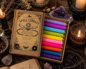 May include: A rectangular cardboard box containing ten thin, textured, hand-rolled beeswax candles in a rainbow of colors. The box lid features black printed text reading Spell Candles, Phoenix Candle Company, and Hand-Rolled Beeswax Candles.