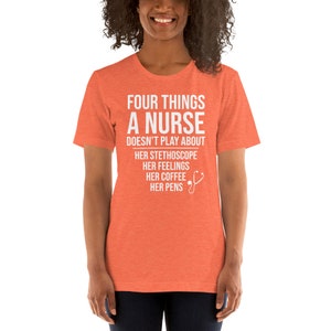 May include: A coral colored t-shirt with white text that reads "Four things a nurse doesn't play about: her stethoscope, her feelings, her coffee, her pens". A white stethoscope icon is next to the text.