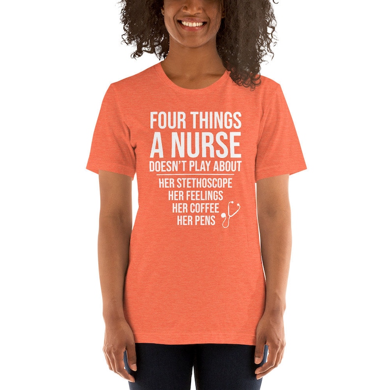 May include: A coral colored t-shirt with white text that reads "Four things a nurse doesn't play about: her stethoscope, her feelings, her coffee, her pens". A white stethoscope icon is next to the text.