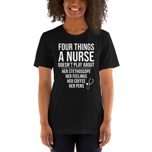 May include: Black t-shirt with white text that reads "Four things a nurse doesn't play about: her stethoscope, her feelings, her coffee, her pens". A small white stethoscope icon is next to the text.