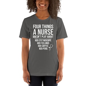 May include: A dark gray t-shirt with white text that reads "Four things a nurse doesn't play about: her stethoscope, her feelings, her coffee, her pens". A white stethoscope icon is next to the text.