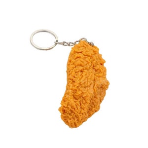 A fried chicken leg keychain. The keychain is made of a soft, realistic-looking material and is attached to a silver metal ring.