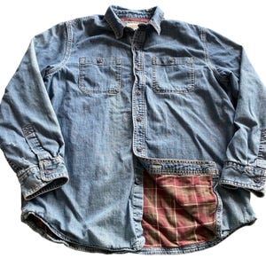 May include: A white ceramic mug with a black handle and the text "But First, Coffee" in a black, bold font. The mug is sitting on a wooden surface. The mug is 4 inches tall.