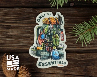 Könnte beinhalten: Ein Aufkleber mit einer Cartoon-Illustration eines grünen Rucksacks, der mit Camping-Essentials gefüllt ist. Der Text "ONLY THE ESSENTIALS" ist auf einem weißen Banner am unteren Rand des Aufklebers geschrieben. Der Text "Alpinacho" ist in kleinerer Schrift unter dem Banner geschrieben. Der Aufkleber befindet sich auf einem hölzernen Hintergrund.