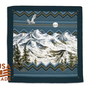 May include: A blue bandana with a white and gold mountain scene and a flying owl. The mountains are covered in snow and the scene is set against a blue sky with a full moon. The bandana has a geometric pattern border.