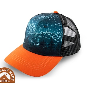 May include: A baseball cap with a black mesh back and an orange brim. The front panel features a dark blue and teal design of a mountain range and constellations. The cap has a small orange button on top. The cap is ethically made in Nepal.