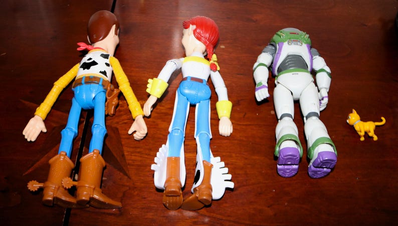 Puede incluir: Tres figuras de acci&oacute;n de personajes de Toy Story: Woody, Jessie y Buzz Lightyear, junto con una peque&ntilde;a figura de gato amarillo. Woody lleva sombrero de vaquero, chaleco y botas. Jessie tiene pelo rojo y un atuendo de vaquera. Buzz lleva un traje espacial.