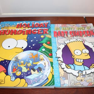 May include: Two The Simpsons books are displayed. The book on the left is titled "Holiday Humdinger" with Bart Simpson holding a snow globe. The book on the right is titled "Big Bratty Book of Bart Simpson".