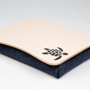 May include: A wooden tray with a blue fabric base and a cutout of a sea turtle. The tray is ideal for holding snacks, drinks, or other items while relaxing on the sofa.