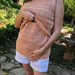 May include: A peach-colored crochet top with a sleeveless design. The top is open in the front, revealing a matching crochet skirt underneath.