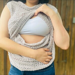 May include: A light brown crochet top with a loose, open weave. The top is worn over a white tank top.