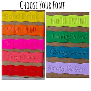 May include: A brown card with the text "CHOOSE YOUR FONT" at the top.  The card is divided into two columns. The left column has five colorful strips with the text "Solid Print", "SKINNY PRINT", "Fancy Cursive", "Elegant Cursive", and "Classy Cursive". The right column has four colorful strips with the text "Bold Print", "Danity Cursive", "Skinny Cursive", and "Swirly Cursive".