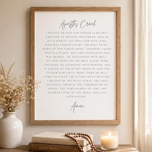 May include: A framed wall art print featuring the Apostles' Creed text in black serif font on a white background. The wooden frame surrounds the text, which begins with the title Apostles' Creed and concludes with the word Amen at the bottom.