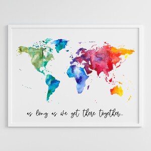 Puede incluir: Una impresión de mapa mundial de acuarela en un marco blanco con el texto "as long as we get there together..." debajo del mapa. El mapa está pintado en tonos de azul, verde, amarillo, naranja y rojo. La impresión se muestra en una pared blanca sobre una mesa de café con dos sillas de mimbre y una planta en maceta.