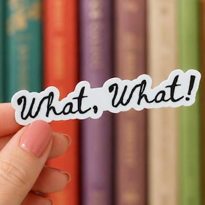 May include: A white die-cut sticker featuring the black handwritten text What, What! with a playful, wavy border. The sticker is held against a background of various colorful book spines, showcasing a clear, bold font style for easy readability.