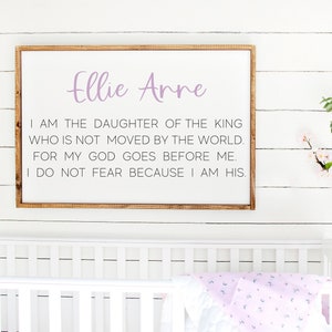 May include: A white wooden sign with a light purple inscription that reads "Ellie Arre" and a quote: "I am the daughter of the King who is not moved by the world. For my God goes before me. I do not fear because I am His."