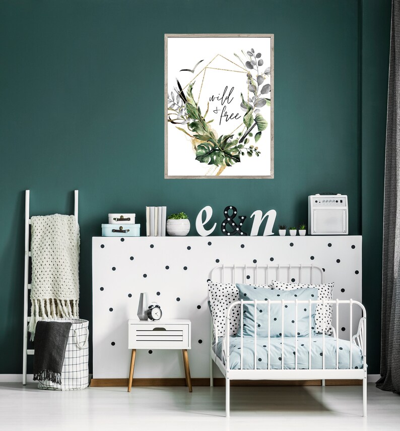 May include: A white framed print with a gold geometric design and green foliage. The print says "wild & free" in black lettering.