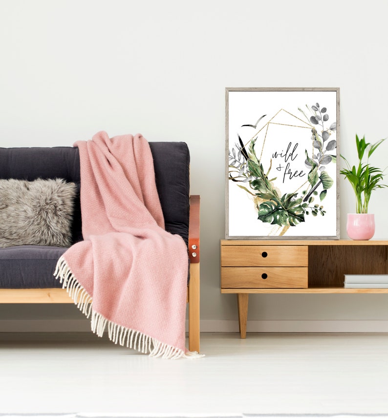 May include: A framed print with a gold geometric design and watercolour greenery. The print features the text "wild + free" in black lettering.