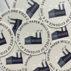 Op de afbeelding: Een set ronde stickers met een fabrieksillustratie en de tekst "Saving Paper Mills One Piece of Evidence at a Time." De stickers zijn beige met zwarte en grijze illustraties.
