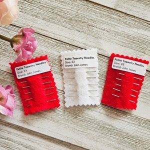 May include: Three packs of Petite Tapestry Needles, each with a different size: 24, 22, and 28. The needles are packaged in red and white felt with a white label that says "Petite Tapestry Needles" and the size and brand, "John James".