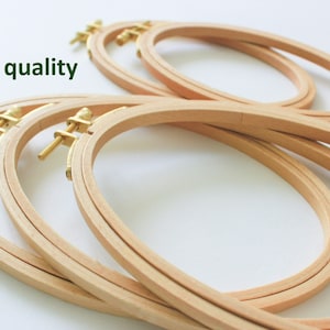 May include: A set of four oval-shaped wooden embroidery hoops with brass screw-on clamps. The hoops are stacked on top of each other.