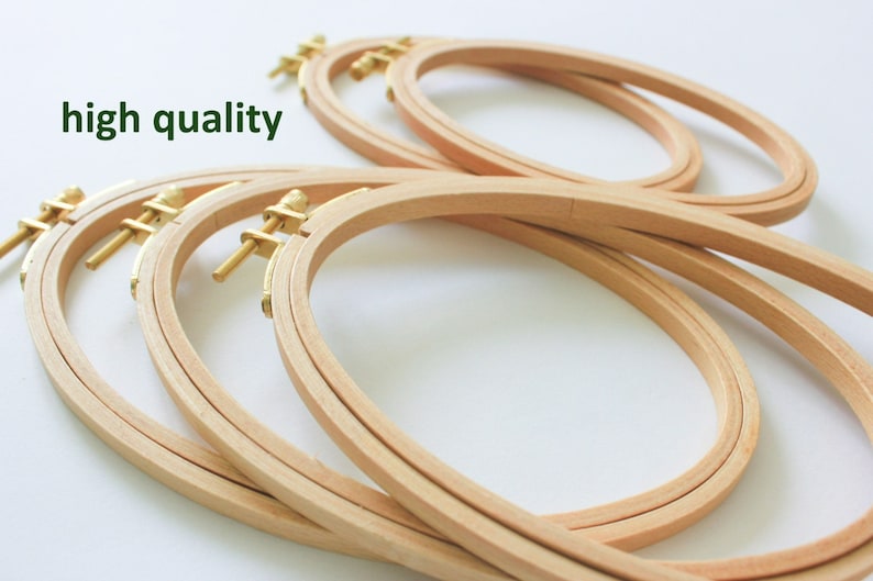 May include: A set of four oval-shaped wooden embroidery hoops with brass screw-on clamps. The hoops are stacked on top of each other.