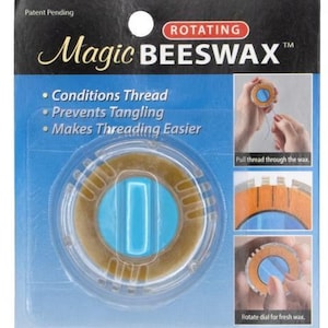 May include: A package for Magic Beeswax, a rotating thread conditioner. The package is blue and black, with the product name in gold script. The product itself is a circular, tan-colored wax disc with a blue center. Text on the package says it conditions thread and prevents tangling.