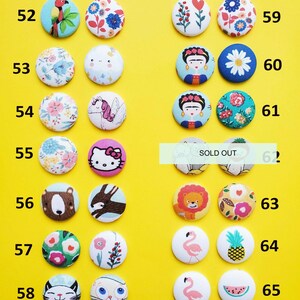 a collection of colorful buttons with various designs, including animals, flowers, and other decorative elements, arranged on a yellow background.