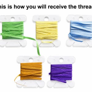 May include: Five white plastic bobbins wrapped with colorful ribbon threads in green, yellow, light blue, gold, and purple. The text "This is how you will receive the threads" is displayed at the top of the image above the bobbins.