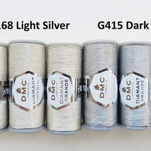 May include: Six spools of D.M.C. Diamant Grande thread in light and dark silver. The labels read "G168 Light Silver" and "G415 Dark Silver". The thread is wound on gray spools with silver labels.