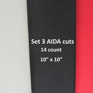 May include: Set of three 10" x 10" Aida fabric squares in white, black, and red. The fabric is 14 count.