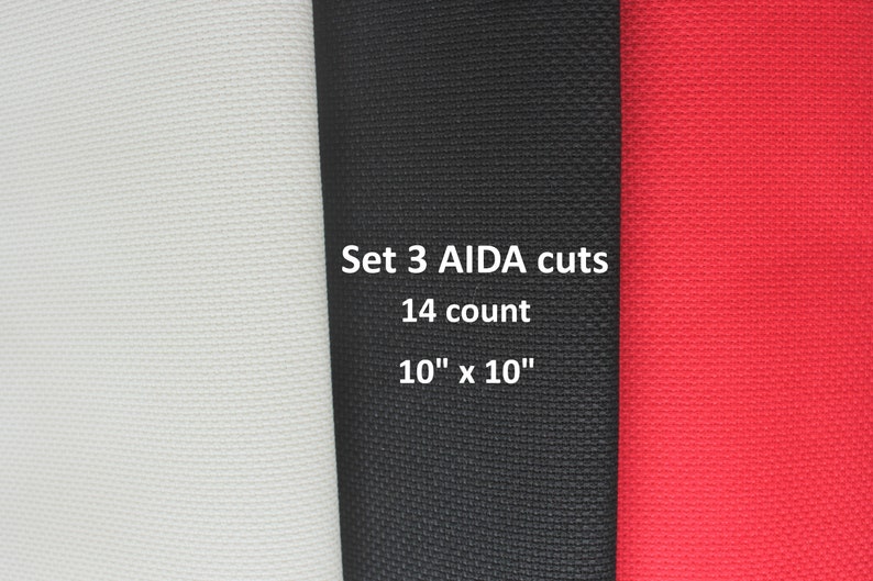 May include: Set of three 10" x 10" Aida fabric squares in white, black, and red. The fabric is 14 count.