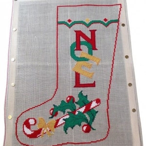 Op de afbeelding: Wit canvas met een rood, groen en geel kerstsokontwerp. De sok is geborduurd met het woord "NOEL" en heeft onderaan een snoepstok en hulstontwerp.