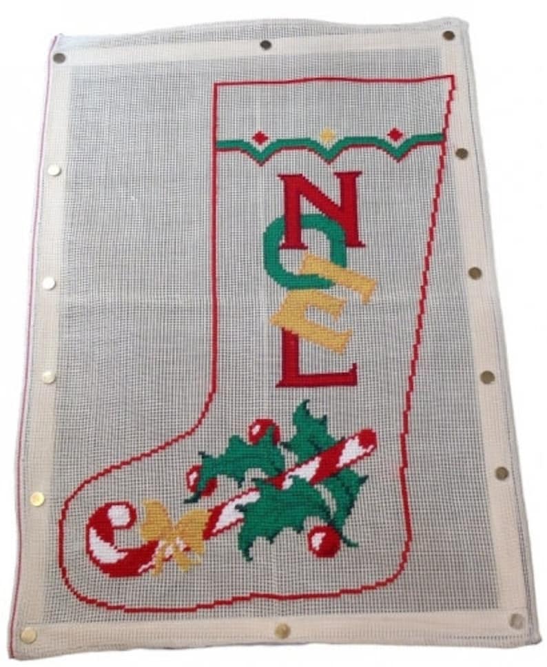 Op de afbeelding: Wit canvas met een rood, groen en geel kerstsokontwerp. De sok is geborduurd met het woord "NOEL" en heeft onderaan een snoepstok en hulstontwerp.