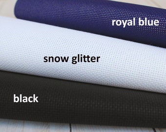 May include: Three rolls of Aida cloth in black, white and royal blue. The white roll has the text "snow glitter" printed on it.