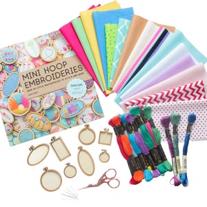 May include: A craft kit for mini hoop embroidery featuring a book titled "Mini Hoop Embroideries" by Sonia Lyne, a variety of colourful fabrics, embroidery floss, wooden hoops, needles, and embroidery scissors.