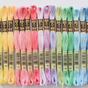 May include: A collection of colorful embroidery floss skeins in a variety of pastel shades, including yellow, pink, purple, green, and blue. Each skein is labeled with a number and the brand name DMC. The floss is neatly arranged, showcasing the range of colors available for needlework projects.