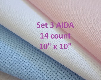 May include: Set of three 10 inch by 10 inch Aida fabric squares in white, light blue, and pink. The fabric is 14 count Aida cloth, used for cross stitch projects.