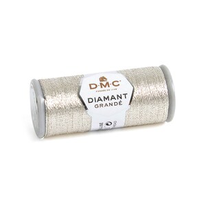 May include: A silver metallic DMC Diamant Grand&eacute; thread spool. The thread is wrapped around a gray plastic spool. The label reads "DMC Diamant Grand&eacute;". This thread is ideal for embroidery and decorative stitching projects.