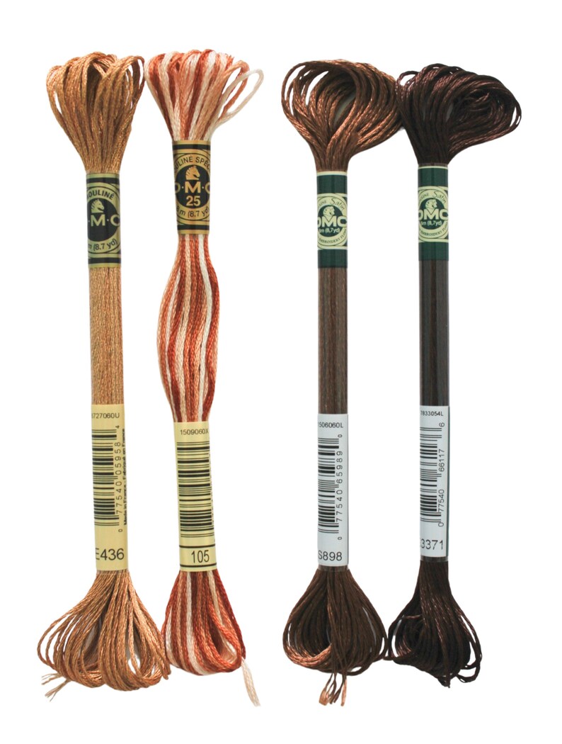 May include: Four spools of DMC embroidery floss in shades of brown, orange, and white. The spools are labeled with the DMC numbers 3371, 5898, 105, and 436.