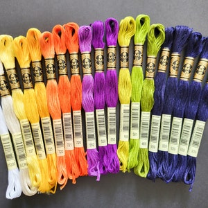 Peut inclure: Assortiment de bobines de fil &agrave; broder DMC de diff&eacute;rentes couleurs, notamment blanc, jaune, orange, violet, vert et bleu. Les bobines sont &eacute;tiquet&eacute;es avec les num&eacute;ros DMC, notamment 727, 725, 722, 552, 550, 168, 581, 469, 606, 906, 939, 539 et 909.