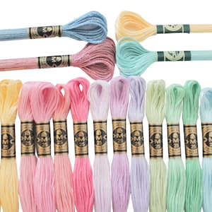 May include: A collection of colorful embroidery floss skeins in various pastel shades, including yellow, pink, blue, and green. Each skein is labeled with "DMC 25". The floss is neatly arranged, showcasing a range of soft, vibrant hues.